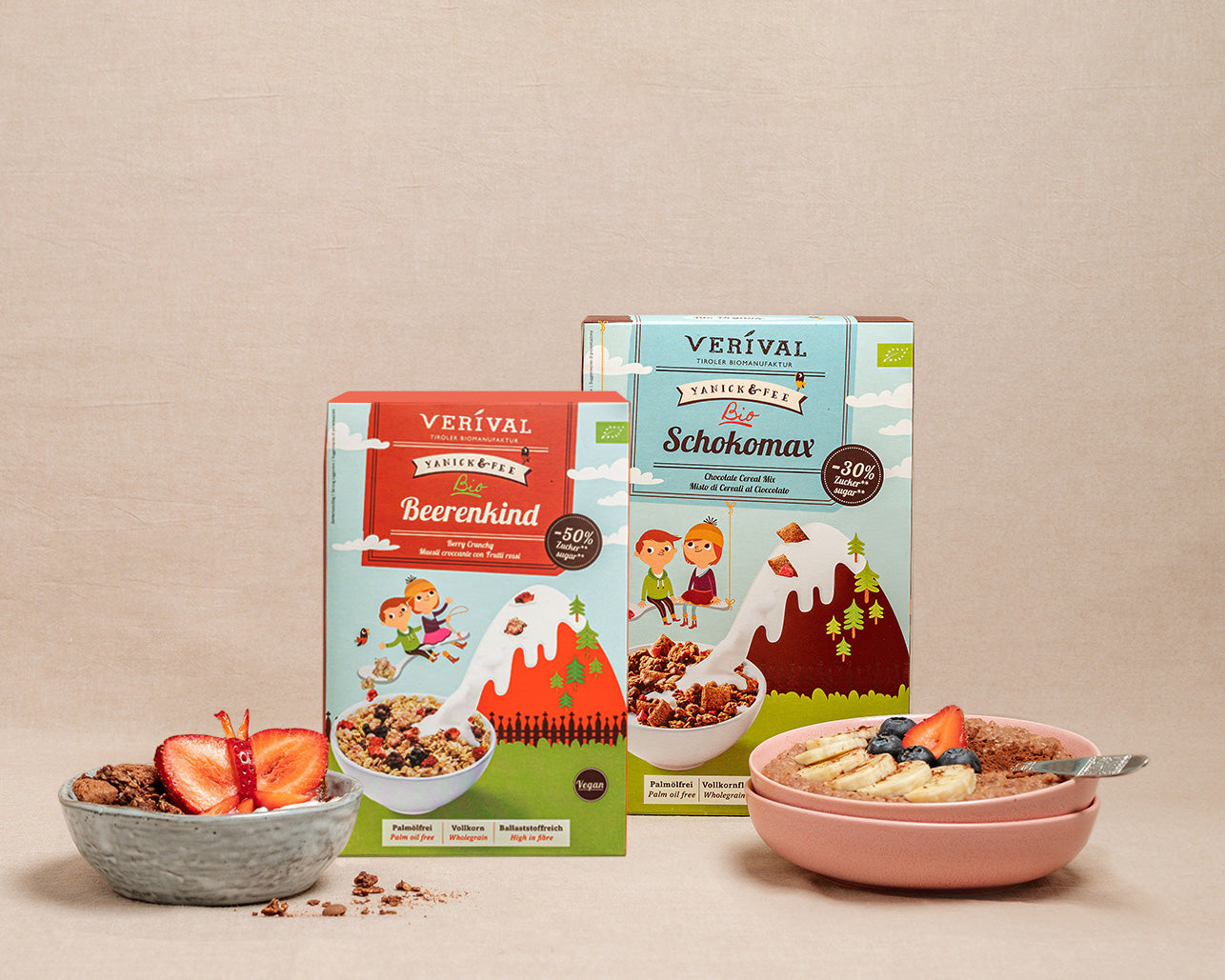 Deux paquets de muesli Verival se trouvent derrière des bols de muesli préparé, garnis de fruits, sur un fond beige.
