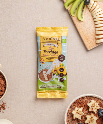 Eine Einzelportionspackung Verival Bio Kids Porridge Kakao-Banane, ein glutenfreier Porridge, garniert mit sternförmigen Bananen, Kiwischeiben, Kakaopulver und saftigen Heidelbeeren – ein geschmackvolles Festmahl, reich an wichtigen Ballaststoffen.