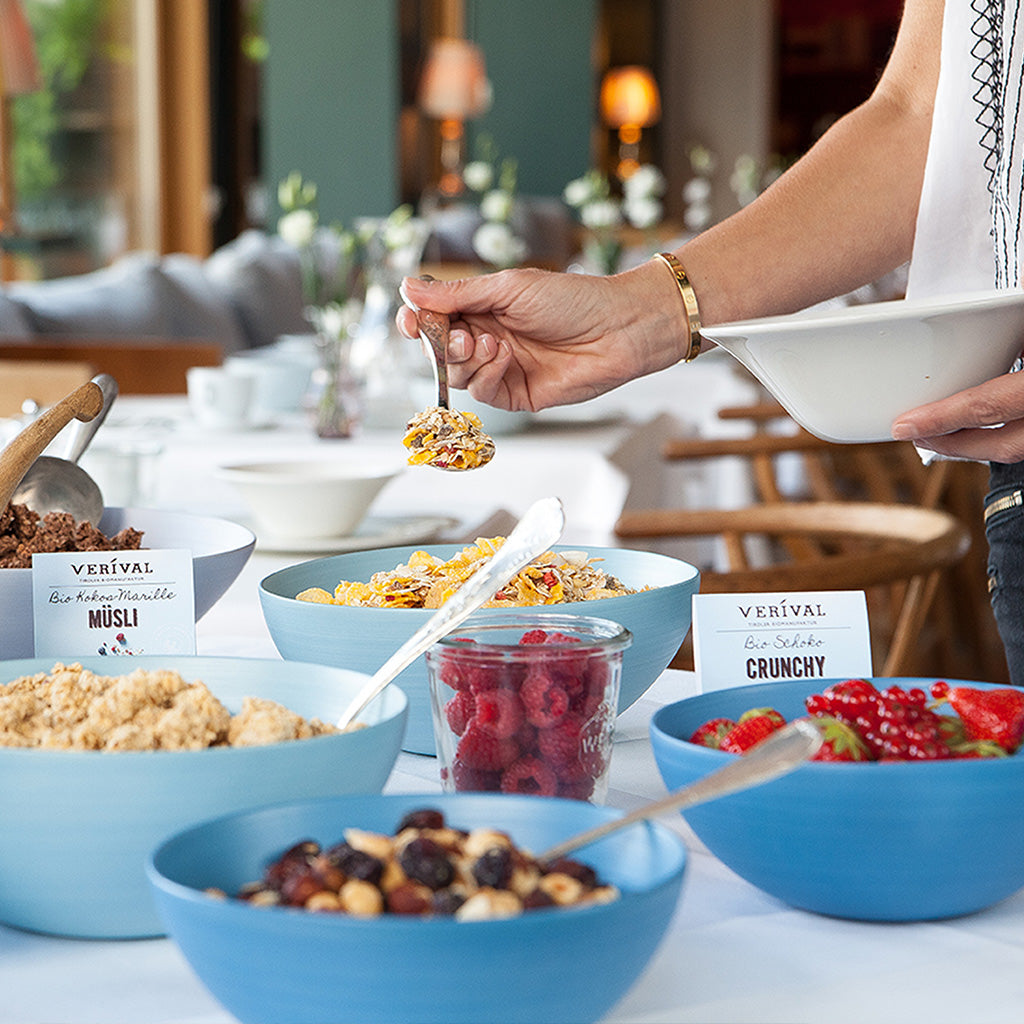An einem Frühstücksbuffet eines Hotels löffelt ein Gast Verival-Müsli in eine Schale.